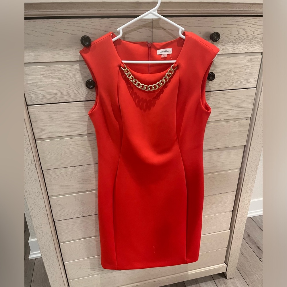 Orange dress with attached gold change necklace.